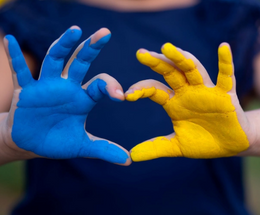 An image of hands in a heart shape in the colours of Ukraine