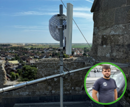 An image of grant recipient next to a broadband aerial placed atop a tall structure in the romney marsh