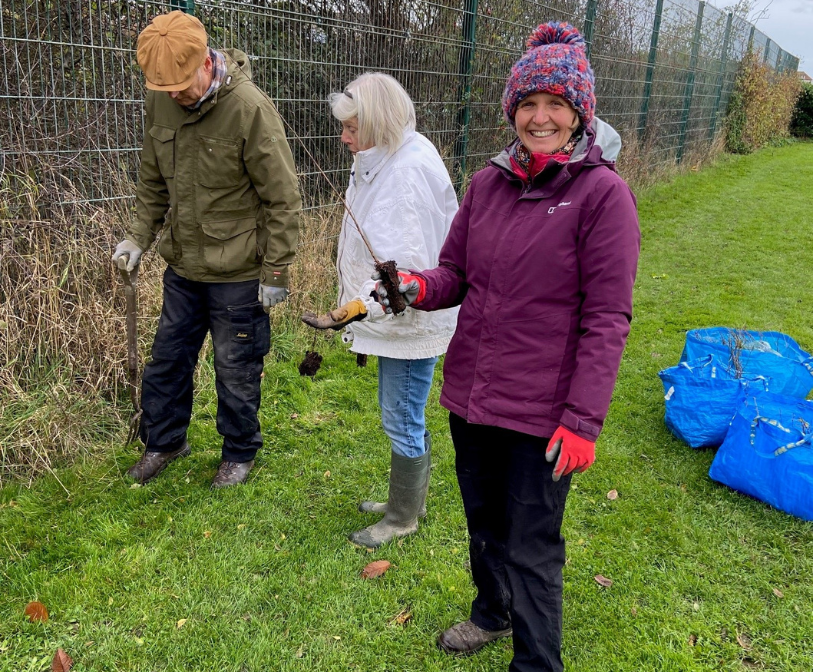 Cllr Anita Jones holding a tree whip before its planted by volunteers